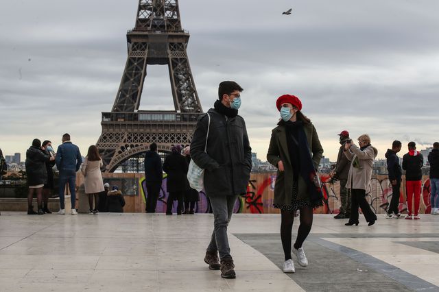 People walk around wearing face masks near the Eiffel Tower.